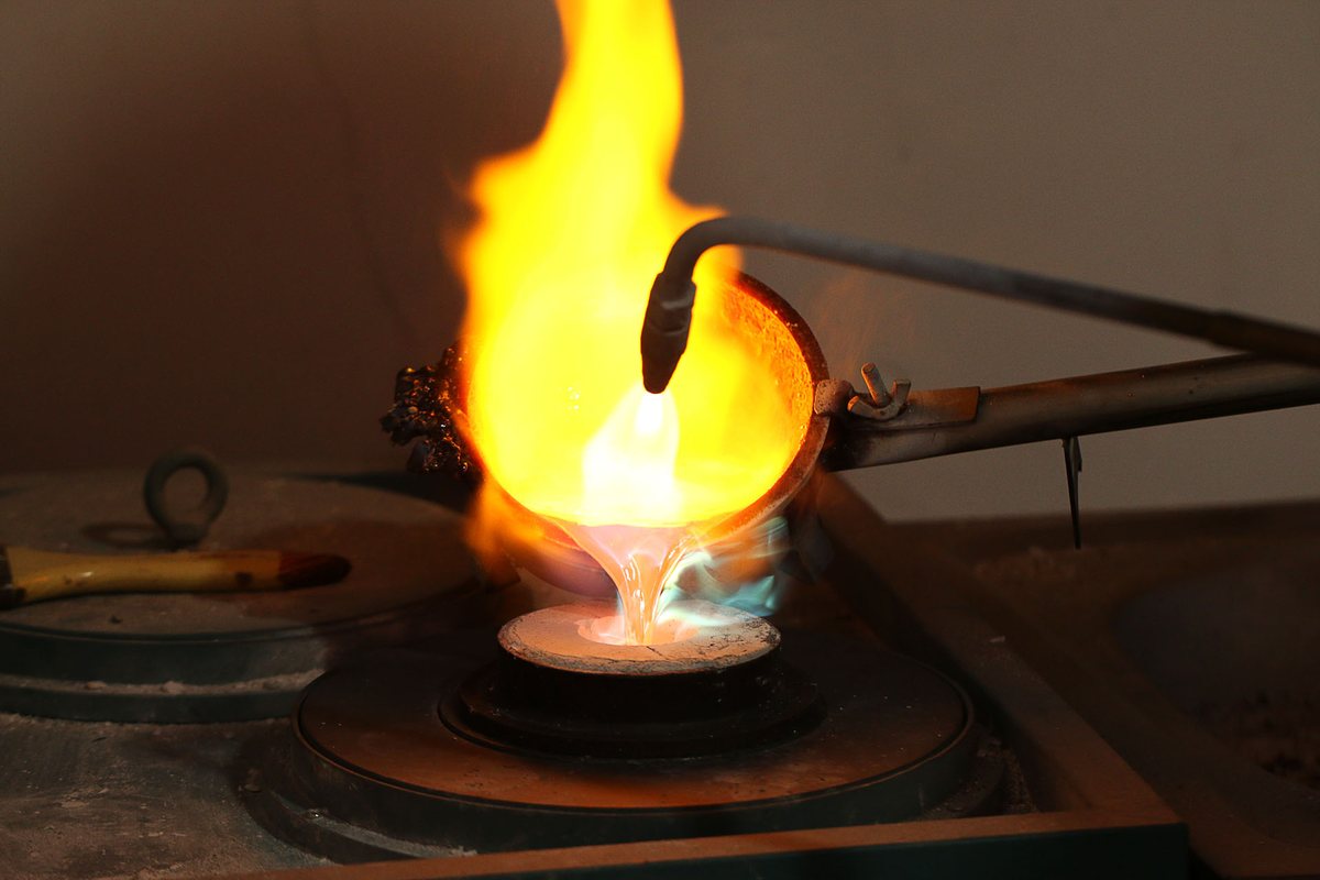 Creuset chauffé au chalumeau qui verse le métal en fusion dans un cylindre de revêtement, lors d'une fonte à la cire perdue