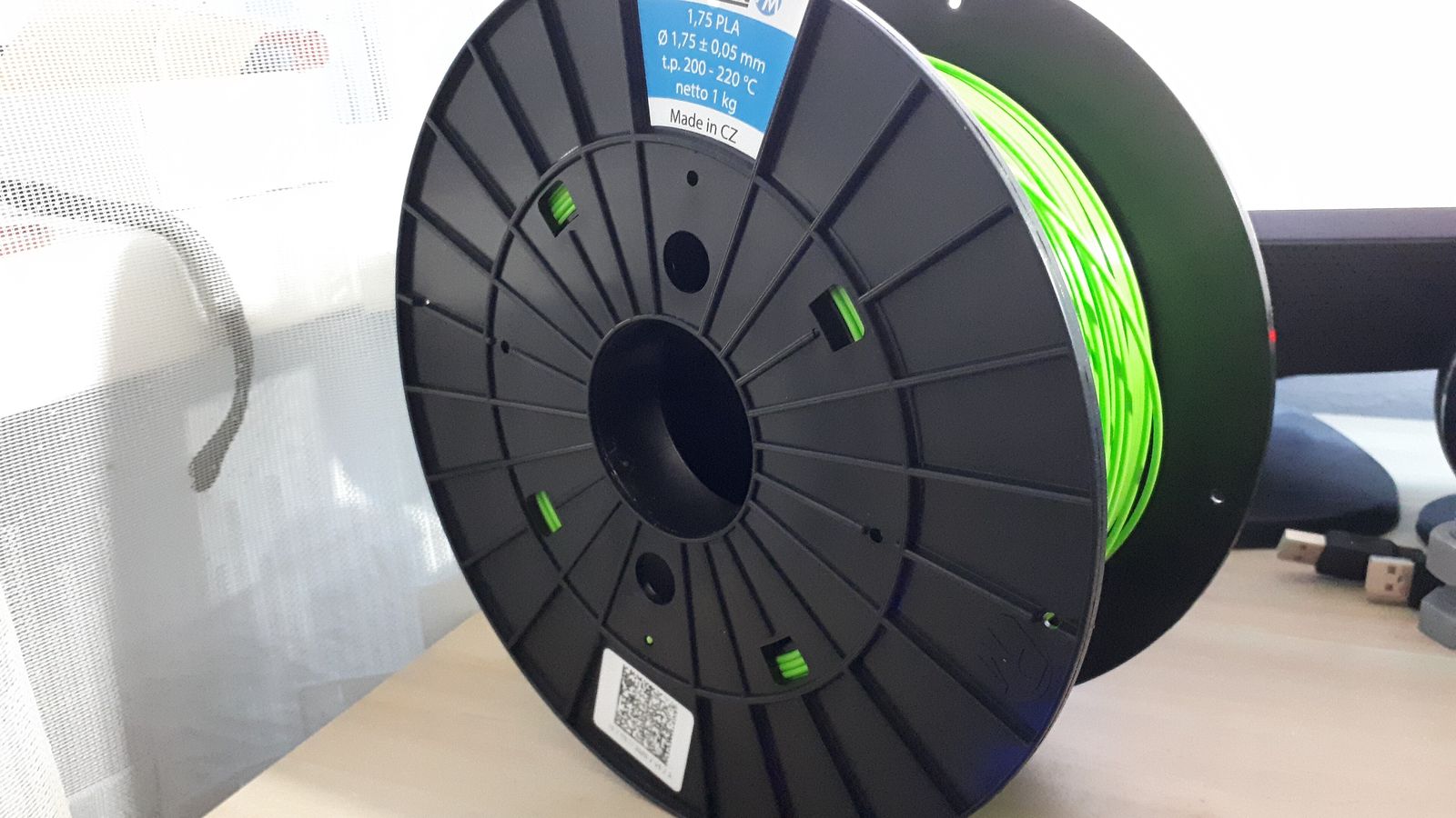 Bobine de filament PLA vert posée sur un bureau