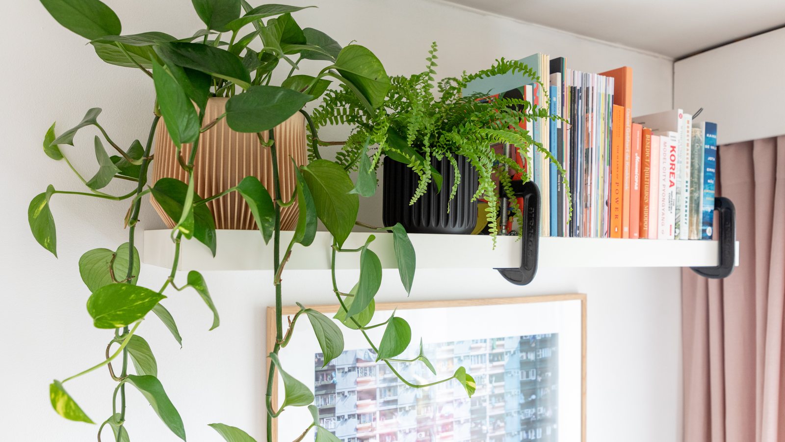 Deux cache-pots imprimés en 3D, l'un plissé couleur sable, l'autre cannelé noir, sur une étagère de salon avec des livres