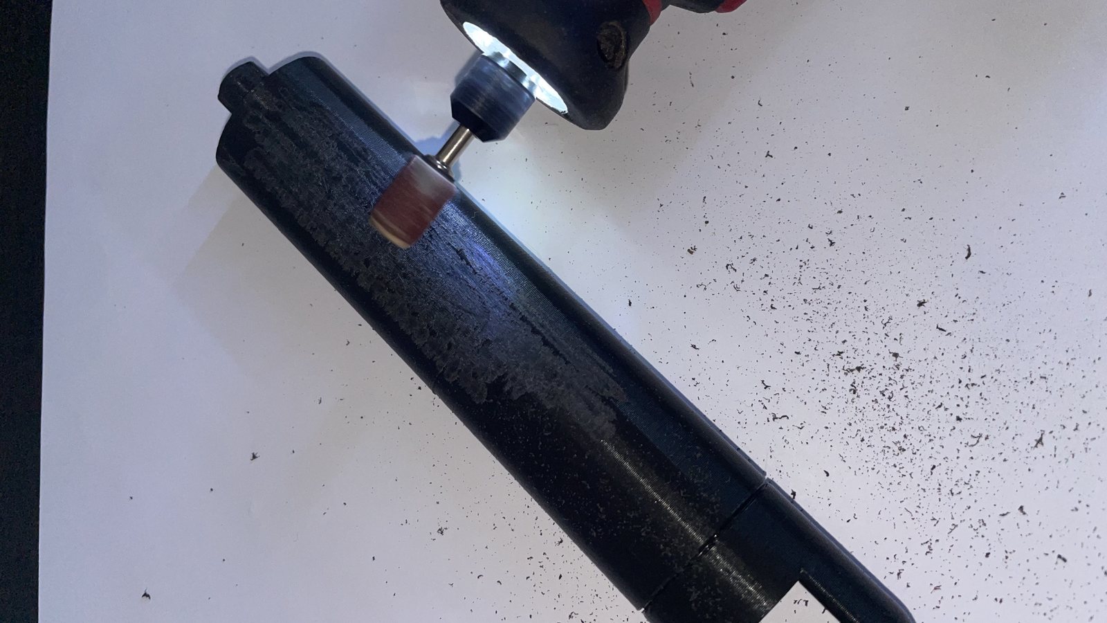 Ponçage à l'outil rotatif d'un tube imprimé en filament noir, stries de couche et poussière de plastique sur la feuille