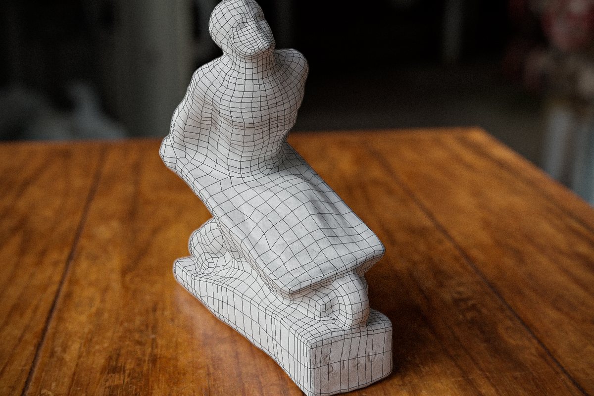 Statuette de plâtre recouverte du maillage issu de son scan 3D, posée sur une table en bois