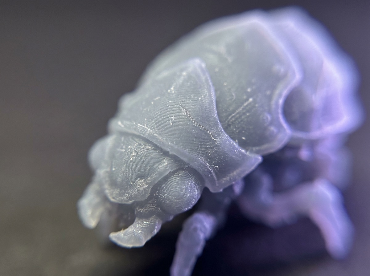 Pièce en résine translucide aux détails fins, sous une lumière violette