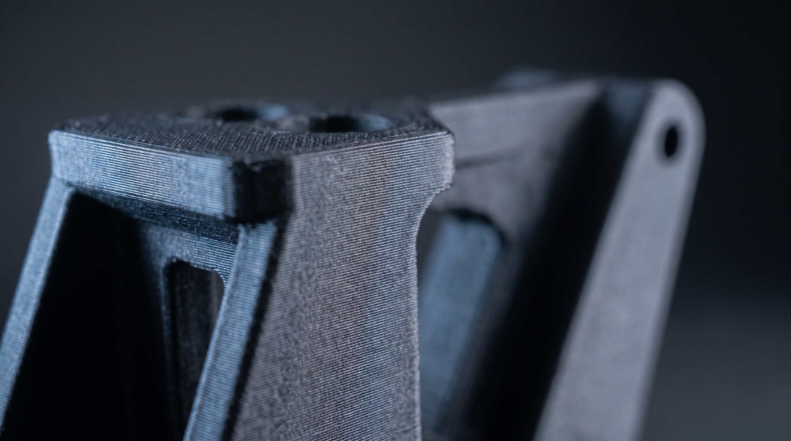 Pièce technique imprimée en 3D, vue en gros plan sur ses arêtes et ses perçages